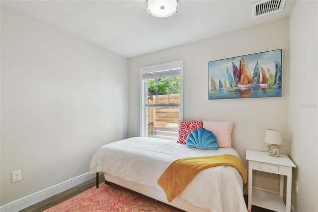 bedroom with baseboards, visible vents, and wood finished floors