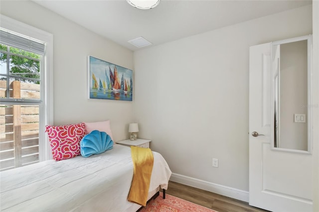 bedroom featuring baseboards, visible vents, and wood finished floors