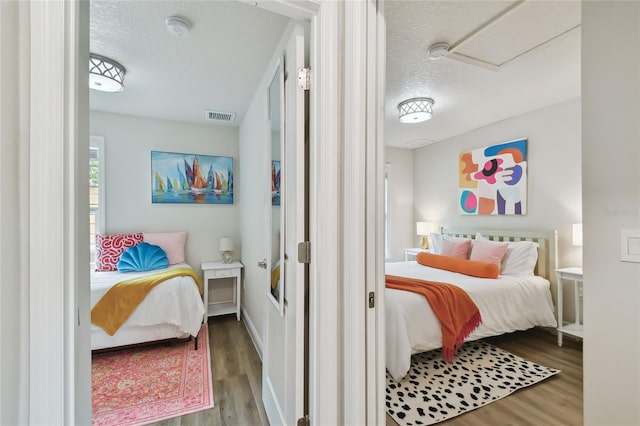 bedroom featuring visible vents, a textured ceiling, and wood finished floors