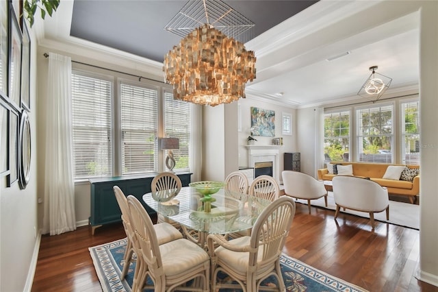dining space with crown molding, a fireplace, visible vents, dark wood-type flooring, and an inviting chandelier