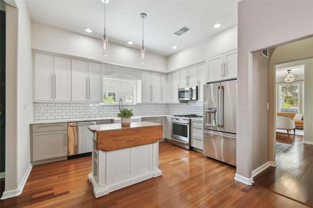 kitchen featuring visible vents, tasteful backsplash, dark wood-type flooring, and stainless steel appliances