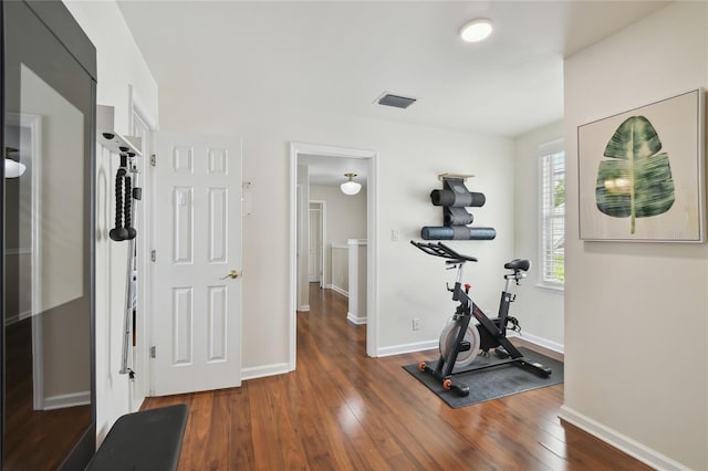 exercise area featuring baseboards, visible vents, and wood-type flooring