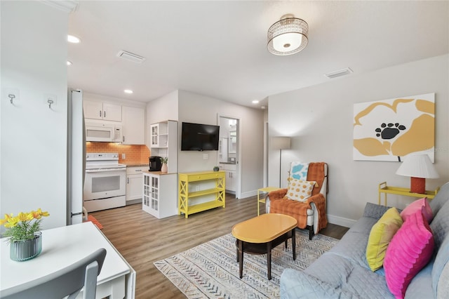 living area featuring wood finished floors, recessed lighting, baseboards, and visible vents
