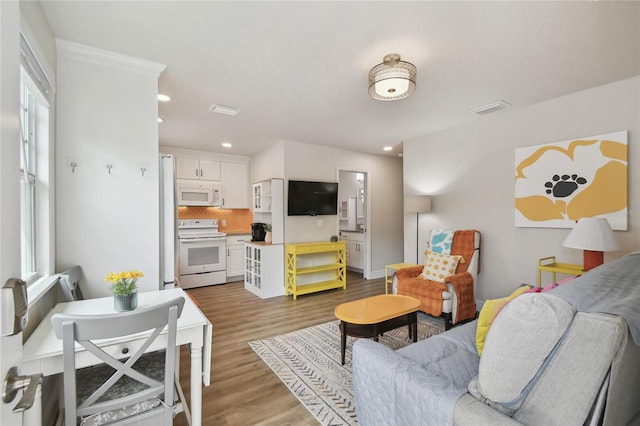 living room with visible vents, wood finished floors, and recessed lighting
