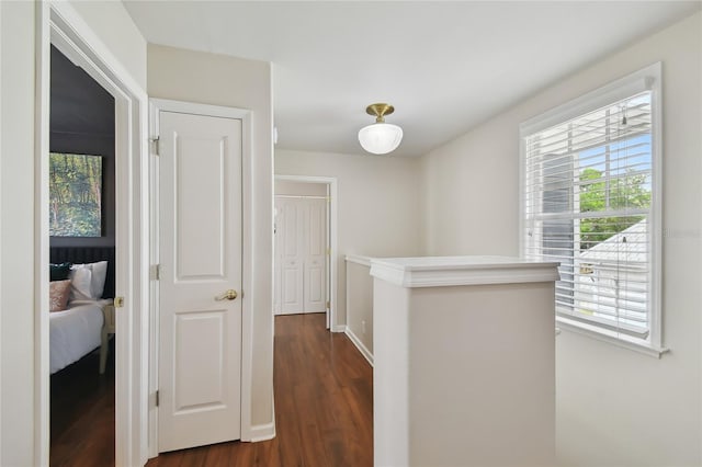 hallway with baseboards, dark wood-style flooring, and an upstairs landing