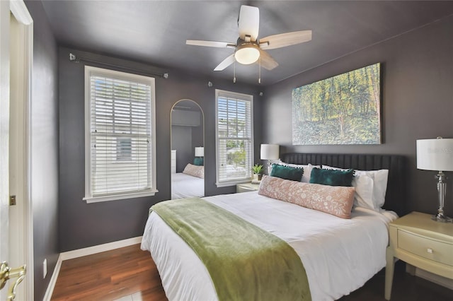 bedroom featuring baseboards, wood finished floors, and a ceiling fan