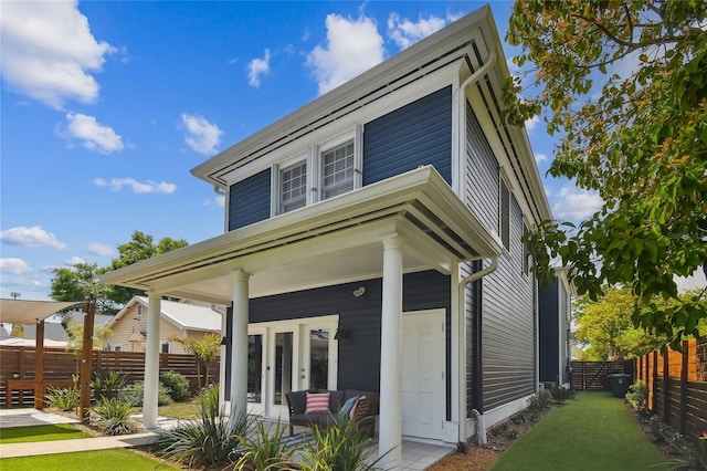 rear view of property with covered porch and fence