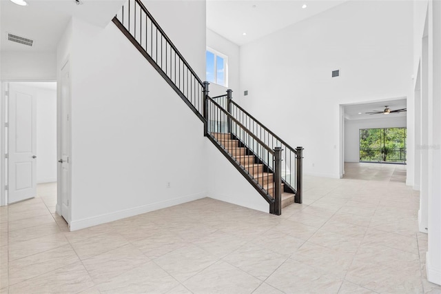 30900 Spruceberry Ct, Wesley Chapel, FL 33543 - stairs with visible vents, baseboards, a ceiling fan, a towering ceiling, and tile patterned flooring