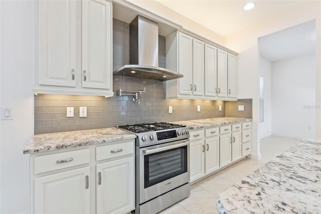 30900 Spruceberry Ct, Wesley Chapel, FL 33543 - kitchen with light stone countertops, stainless steel gas stove, wall chimney exhaust hood, and decorative backsplash