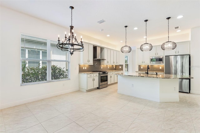 30900 Spruceberry Ct, Wesley Chapel, FL 33543 - kitchen featuring a notable chandelier, wall chimney range hood, appliances with stainless steel finishes, light stone countertops, and backsplash