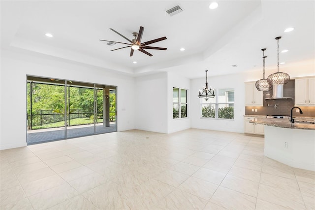 30900 Spruceberry Ct, Wesley Chapel, FL 33543 - unfurnished living room featuring recessed lighting, ceiling fan with notable chandelier, a sink, and a raised ceiling