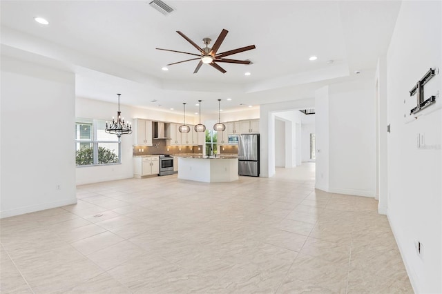 30900 Spruceberry Ct, Wesley Chapel, FL 33543 - unfurnished living room featuring a tray ceiling, ceiling fan with notable chandelier, visible vents, and recessed lighting