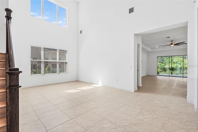 30900 Spruceberry Ct, Wesley Chapel, FL 33543 - unfurnished living room featuring visible vents, baseboards, light tile patterned floors, a ceiling fan, and a tray ceiling