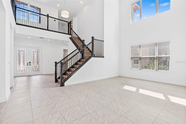 30900 Spruceberry Ct, Wesley Chapel, FL 33543 - unfurnished living room featuring french doors, a healthy amount of sunlight, a towering ceiling, and stairs