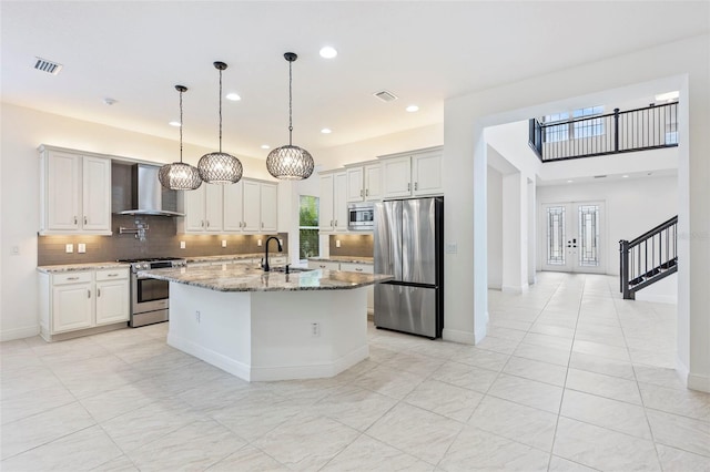 30900 Spruceberry Ct, Wesley Chapel, FL 33543 - kitchen with wall chimney range hood, visible vents, a sink, and appliances with stainless steel finishes