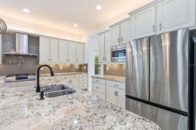 30900 Spruceberry Ct, Wesley Chapel, FL 33543 - kitchen with wall chimney exhaust hood, appliances with stainless steel finishes, light stone counters, a sink, and decorative backsplash