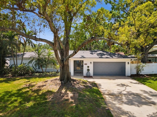 1666 N Dakota Ave NE, Saint Petersburg, FL 33703 - view of front of house featuring a front lawn, fence, a garage, and concrete driveway