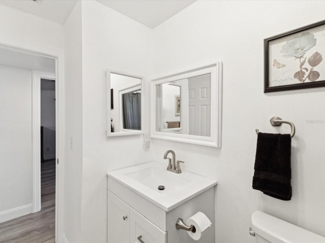 1666 N Dakota Ave NE, Saint Petersburg, FL 33703 - half bathroom with toilet, vanity, baseboards, and wood finished floors