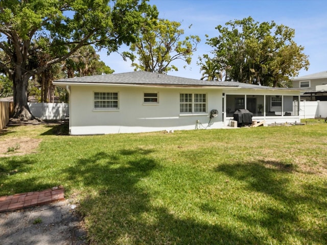 1666 N Dakota Ave NE, Saint Petersburg, FL 33703 - rear view of property featuring a fenced backyard, a lawn, stucco siding, and a sunroom