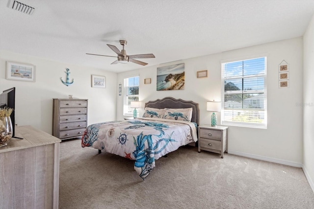 carpeted bedroom featuring baseboards, visible vents, a textured ceiling, and a ceiling fan