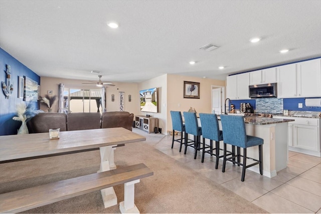 dining space featuring a ceiling fan, light tile patterned floors, a textured ceiling, and visible vents