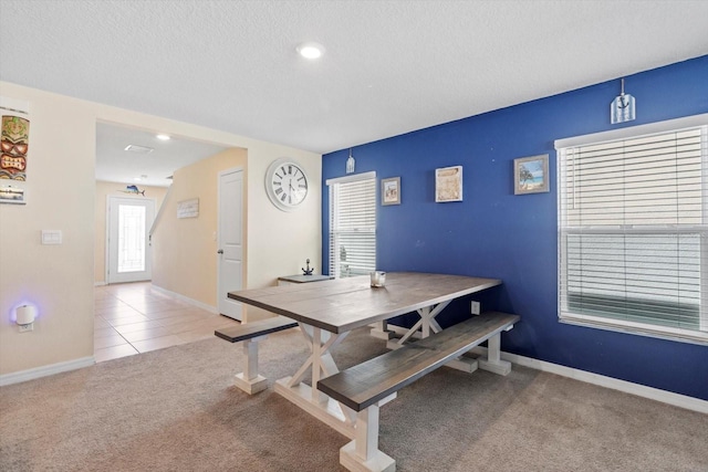 carpeted dining space featuring tile patterned floors, baseboards, and a textured ceiling
