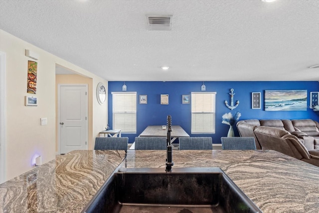 kitchen with open floor plan, visible vents, a sink, and a textured ceiling