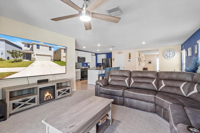 living room with ceiling fan, visible vents, recessed lighting, and light carpet