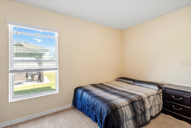 bedroom with light colored carpet and baseboards