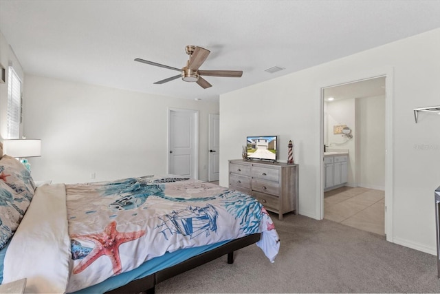 carpeted bedroom featuring baseboards, ensuite bathroom, visible vents, and a ceiling fan