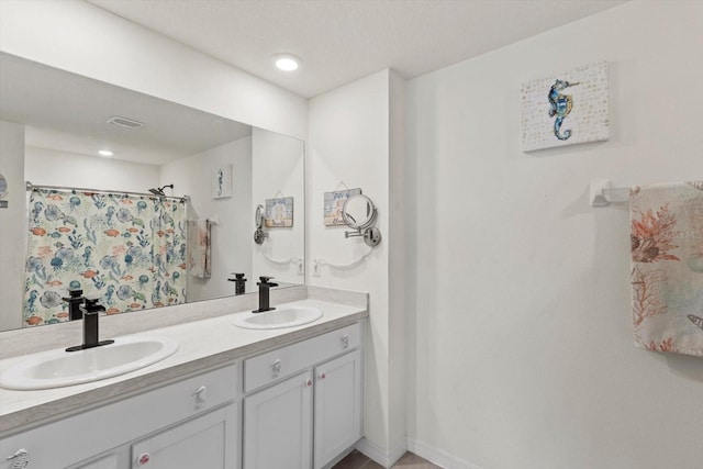 full bath featuring a shower with curtain, double vanity, a sink, and baseboards