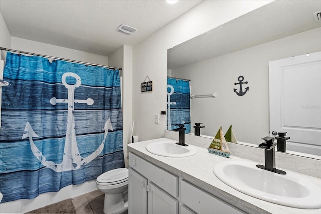 bathroom featuring double vanity, toilet, tile patterned flooring, and a sink