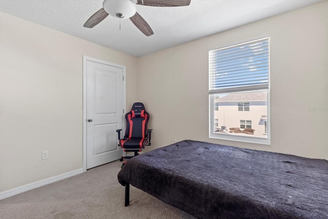 carpeted bedroom featuring a ceiling fan, baseboards, and a textured ceiling