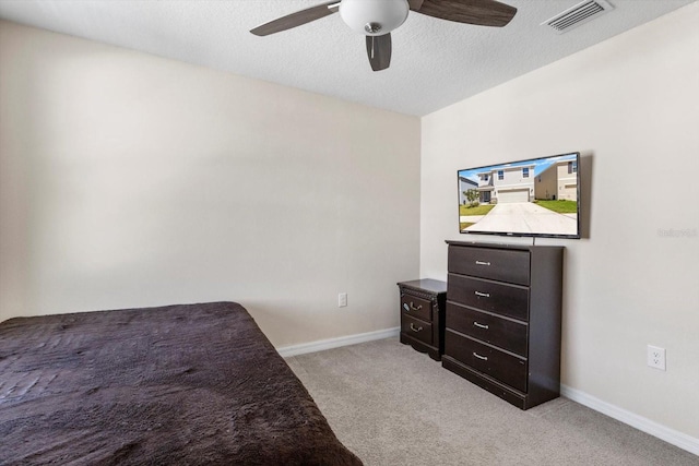 bedroom with a textured ceiling, visible vents, baseboards, a ceiling fan, and light colored carpet
