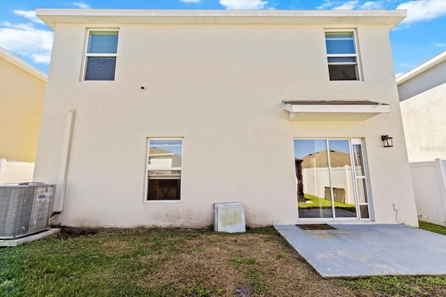 rear view of house featuring stucco siding, fence, central AC, a yard, and a patio area
