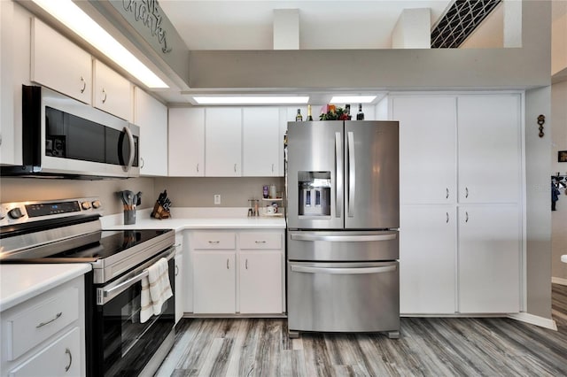 kitchen with light wood finished floors, light countertops, white cabinets, and stainless steel appliances
