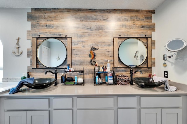 full bath featuring wood walls, double vanity, and a sink