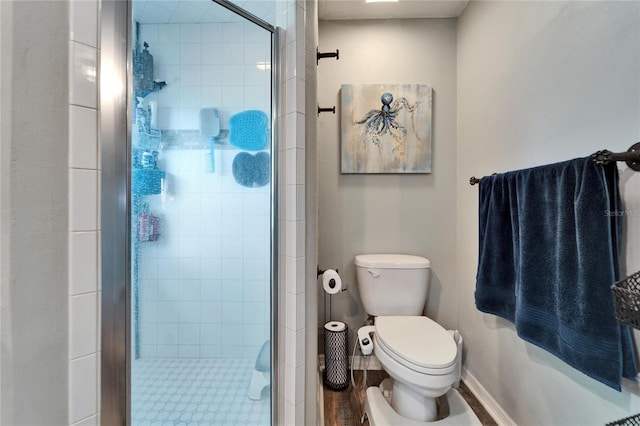 full bath with toilet, a stall shower, and baseboards
