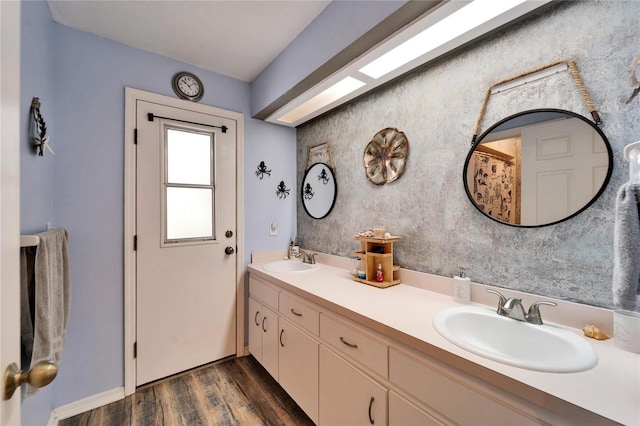 full bath featuring wood finished floors, double vanity, and a sink