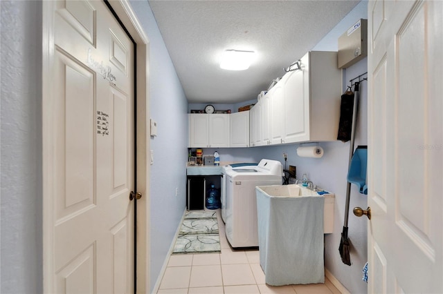 clothes washing area with separate washer and dryer, baseboards, light tile patterned floors, a textured ceiling, and cabinet space