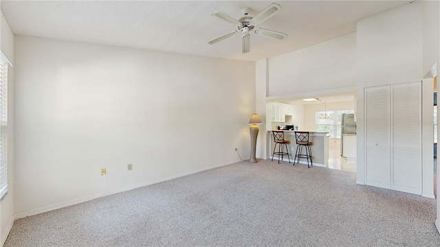 living area with light carpet, a ceiling fan, and baseboards