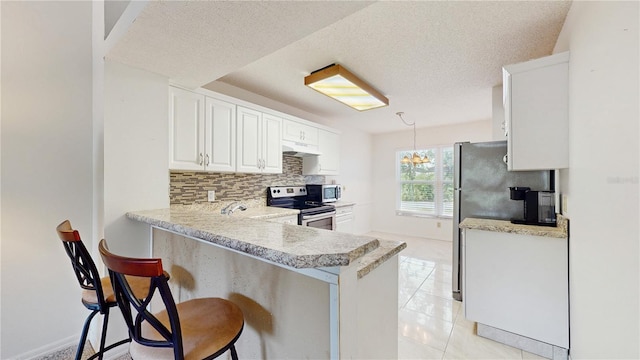 kitchen with stainless steel appliances, under cabinet range hood, light countertops, decorative backsplash, and a peninsula