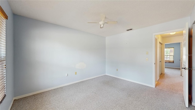 spare room with light carpet, ceiling fan, baseboards, and a fireplace
