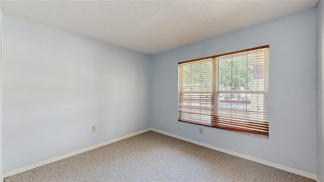 spare room featuring plenty of natural light, carpet, baseboards, and a textured ceiling