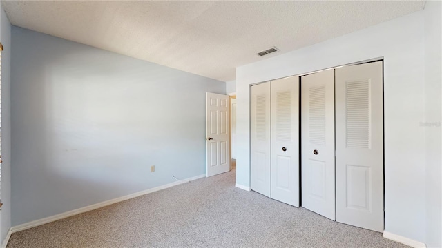 unfurnished bedroom with carpet flooring, a closet, baseboards, and a textured ceiling