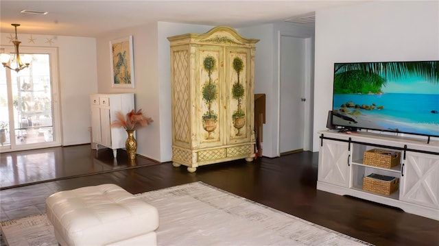 living area with dark wood-type flooring and an inviting chandelier