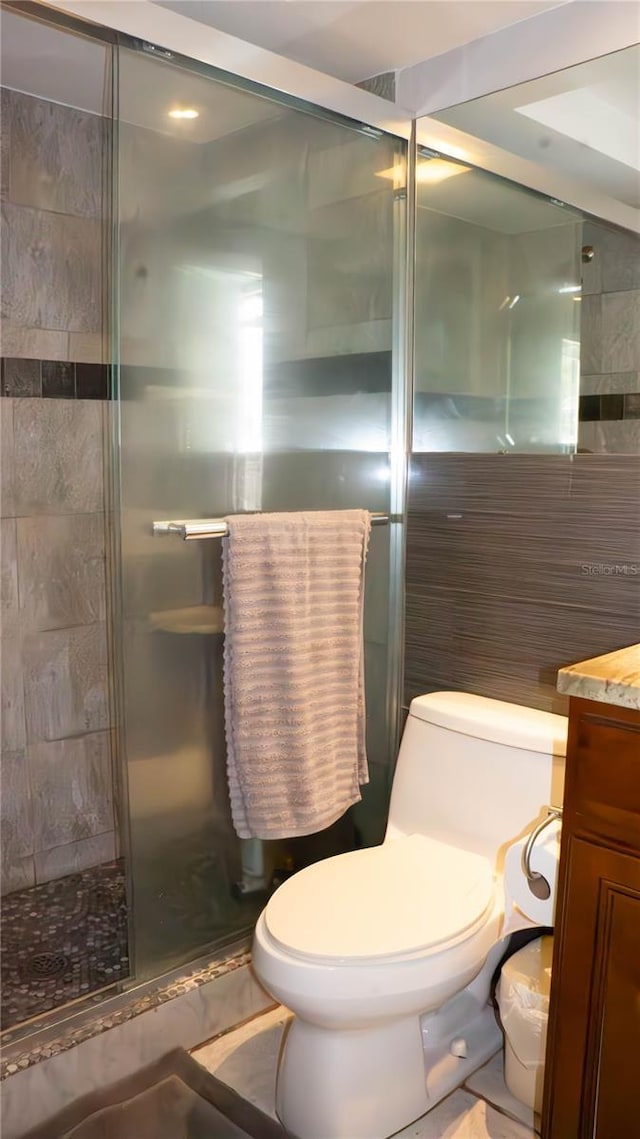 bathroom featuring a stall shower, tile walls, toilet, and vanity