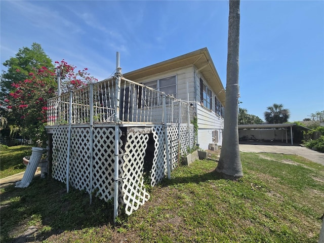 view of side of home with a yard, a wooden deck, and driveway