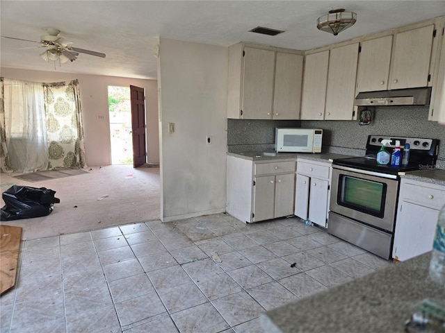 kitchen with white microwave, stainless steel range with electric stovetop, visible vents, under cabinet range hood, and decorative backsplash