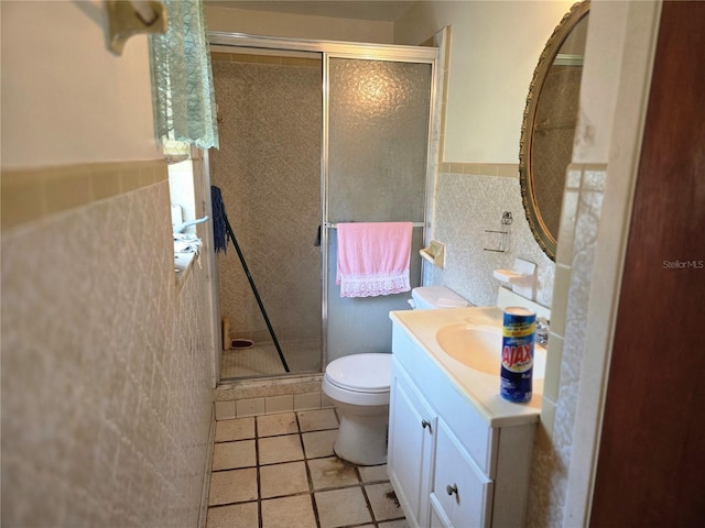 bathroom featuring vanity, a wainscoted wall, toilet, tile walls, and a stall shower